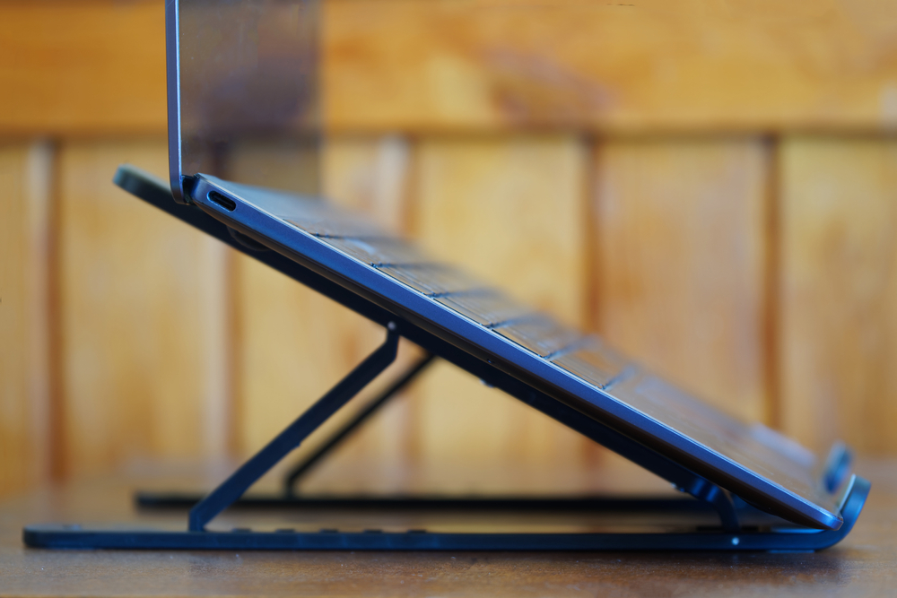 A laptop on a wooden table stand.