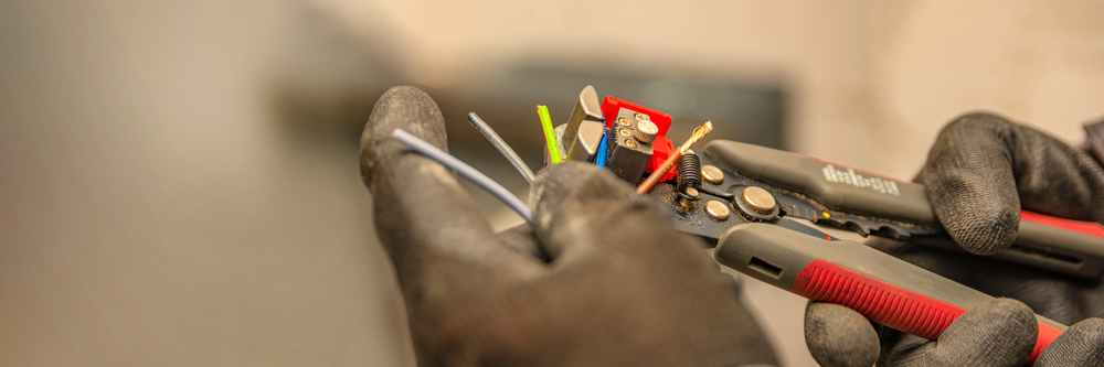 Wire strippers. The electrician cleans the protective insulation from the wire using a wire stripper. The process of connecting wires. close-up