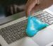 Cleaning a laptop keyboard with soft blue absorbing gel or compound to remove dirt, dust, germs and bacteria, hygiene procedure for a healthy office workplace, copy space, selected focus